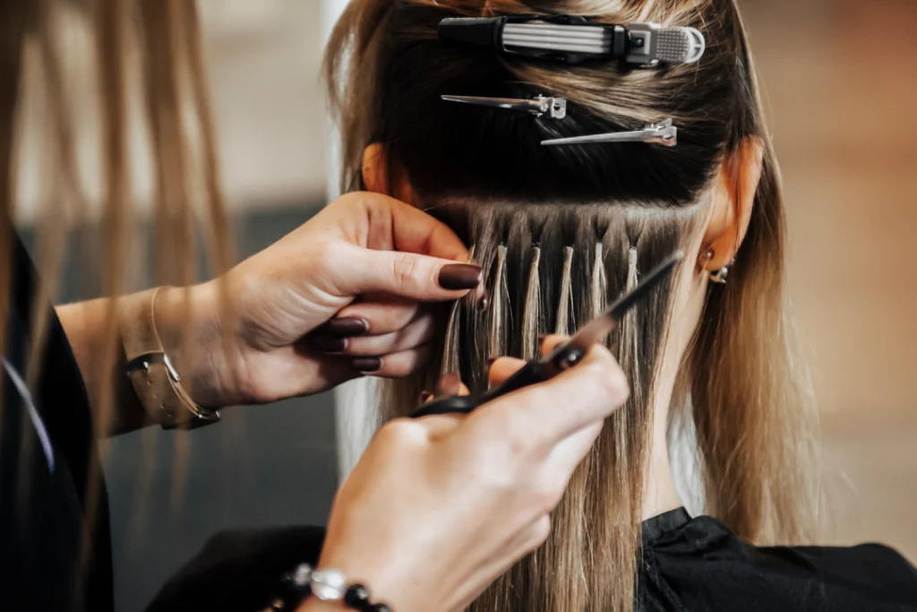 Professional stylist applying hair extensions in a salon.