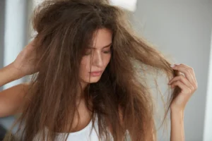 Woman examining her dry, tangled hair before hair treatment.