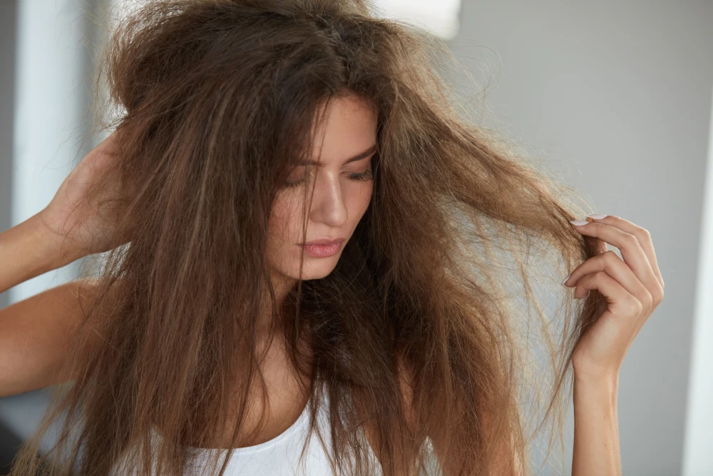 Woman examining her dry, tangled hair before hair treatment.
