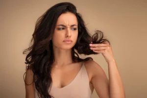 Woman examining dry and damaged strands needing hair repair.